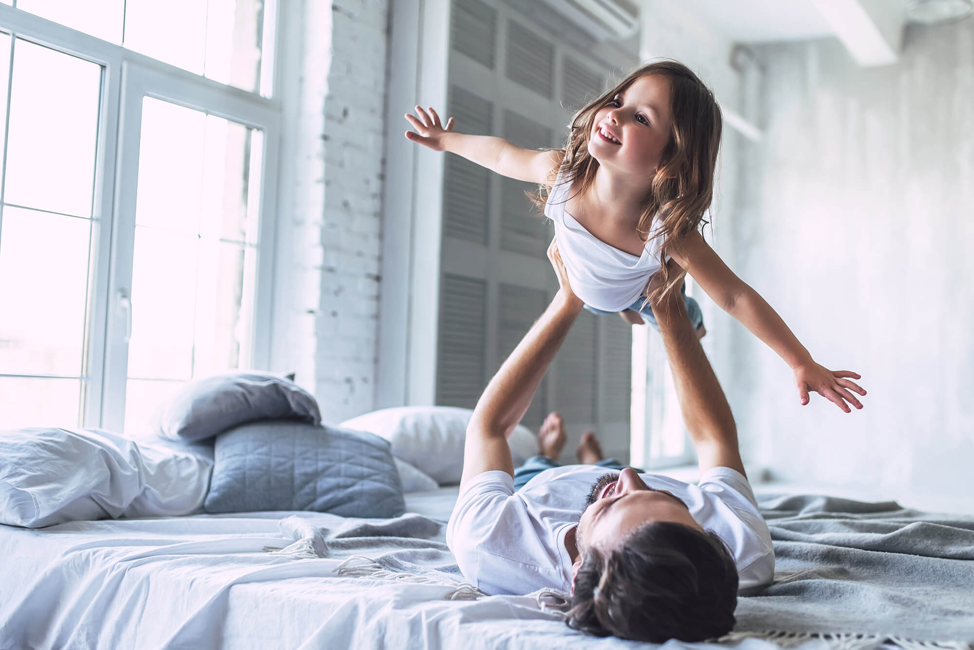 Vater und Tochter liegen im Bett und spielen