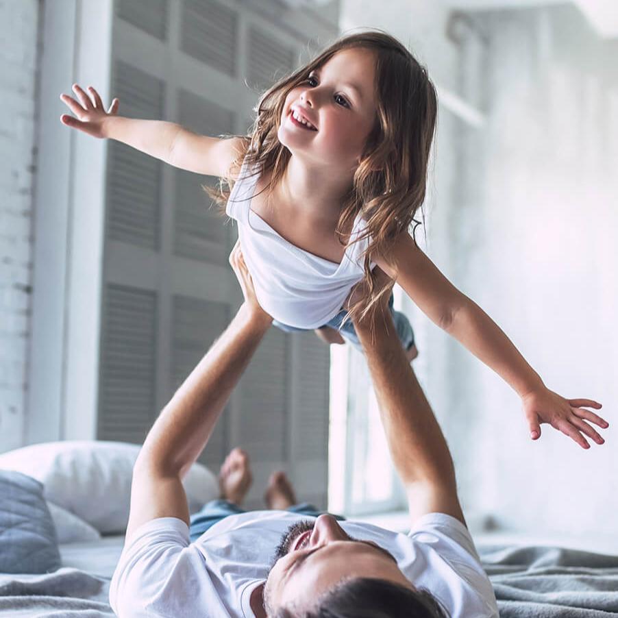 Vater und Tochter liegen im Bett und spielen